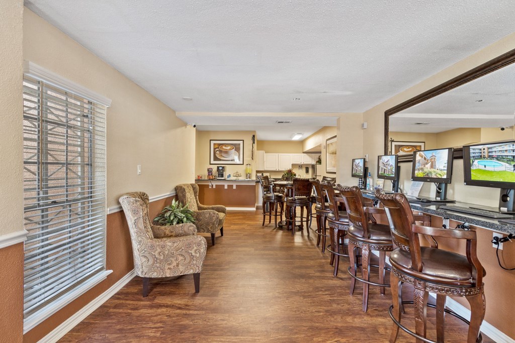 a room with a table and chairs and a kitchen in the background
