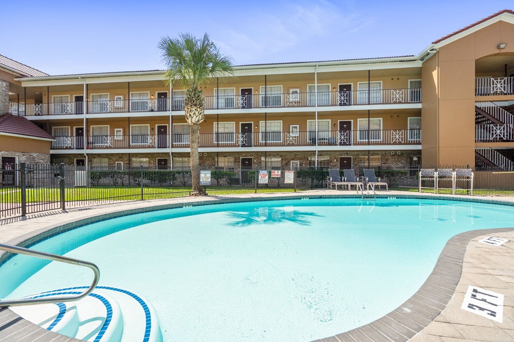 a swimming pool with a palm tree in front of a yellow building
