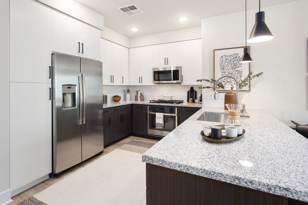 A modern kitchen with a granite countertop and stainless steel appliances.