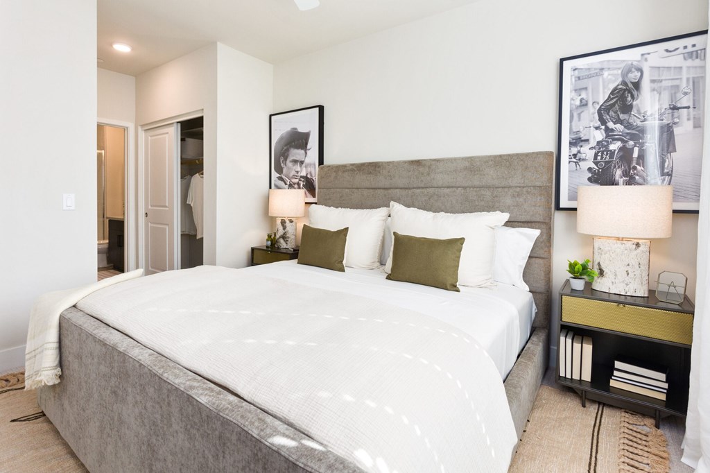 A bedroom with a large bed and two lamps on the side tables.