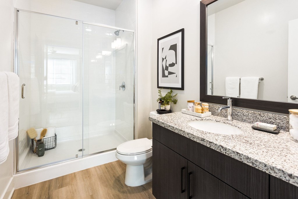 A bathroom with a toilet, sink, and mirror.