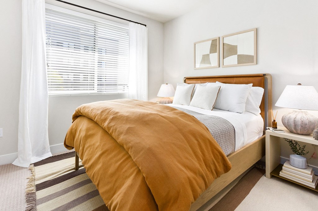 A bedroom with a bed covered in an orange comforter.