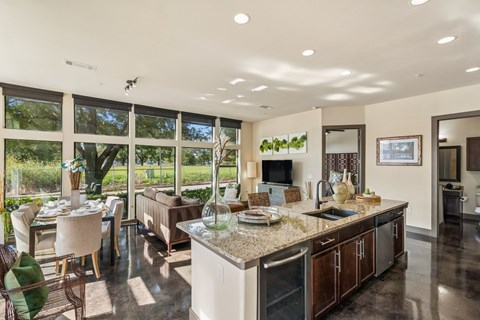 A modern kitchen with a large island and a dining table with chairs.