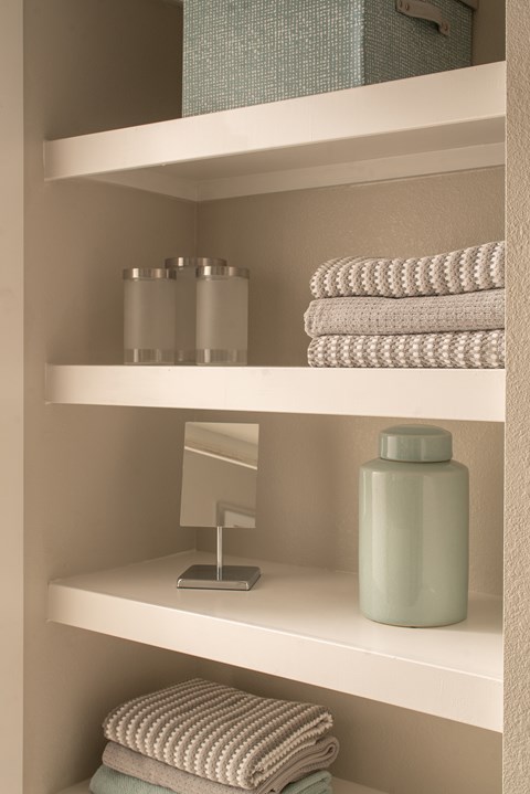 A bathroom shelf with towels and a bottle.