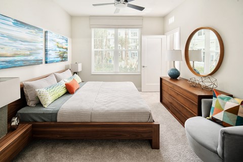 A bedroom with a bed, a chair, and a painting on the wall.