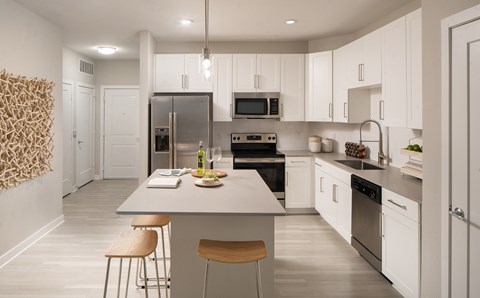 A modern kitchen with white cabinets and stainless steel appliances.