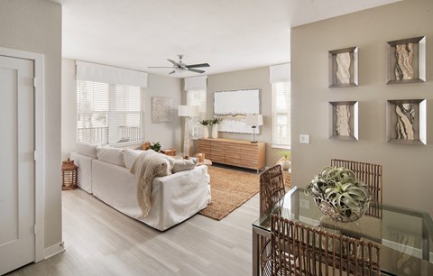 A living room with a white couch and a glass table.