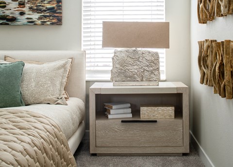 A bedroom with a bed, nightstand, and a painting on the wall.