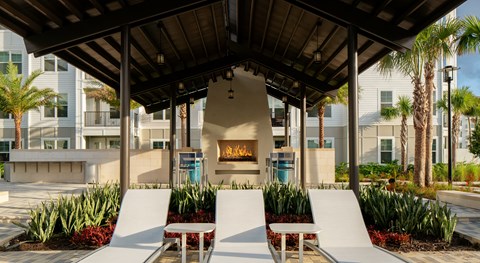 A modern outdoor seating area with white chairs and a fireplace.