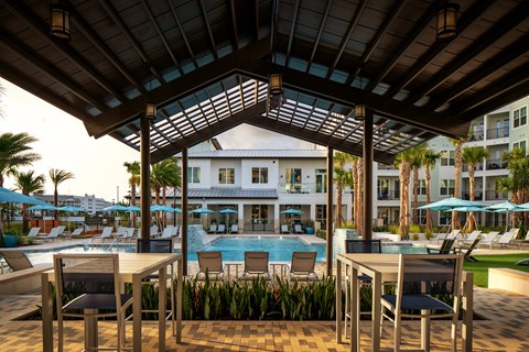 A poolside area with a table and chairs under a roof.