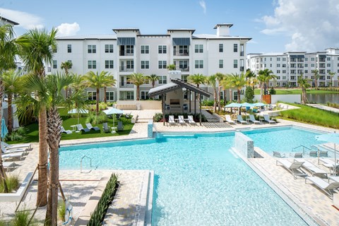 A large swimming pool surrounded by palm trees and lounge chairs.