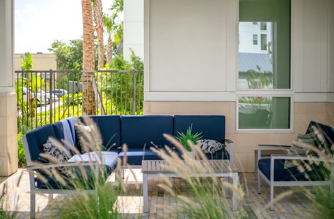 A blue couch is in front of a white building with a window.