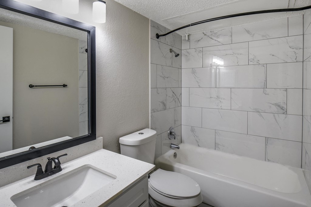 a bathroom with a sink toilet and tub and a mirror