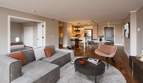 A grey couch with orange pillows sits in a modern living room.