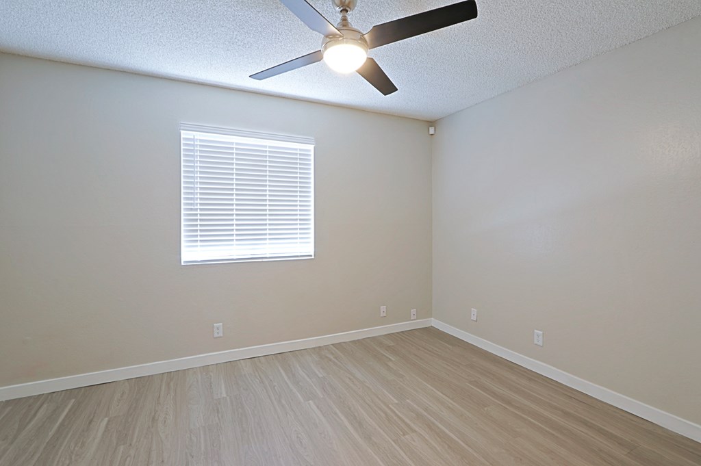 an empty bedroom with a ceiling fan and a window