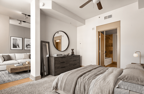 A bedroom with a large bed, a dresser, and a mirror.