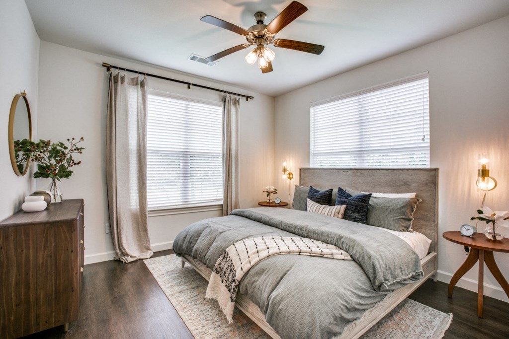 a bedroom with two windows and a ceiling fan