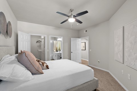 A bedroom with a large bed and a ceiling fan.