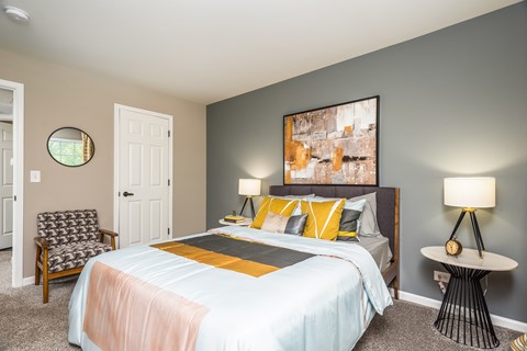 A bedroom with a bed, chair, and painting on the wall.