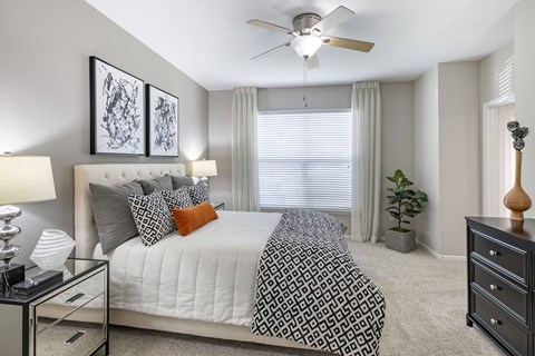 A bedroom with a bed, nightstand, and a ceiling fan.