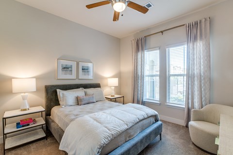 A bedroom with a bed, chair, and two lamps.