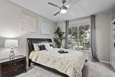 A bedroom with a bed, nightstand, and a ceiling fan.