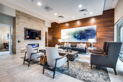 A modern living room with a stone fireplace and a large abstract painting on the wall.