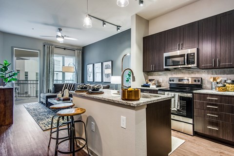A kitchen with a bar stool and a countertop with a plant on it.