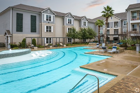 A large swimming pool in front of apartment buildings.