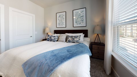 A bedroom with a large bed and two lamps.