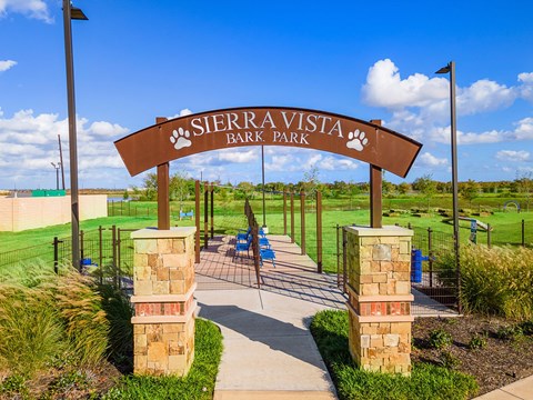 A sign that says Sierra Vista Bark Park in front of a playground.