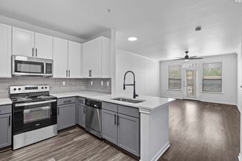 an empty kitchen with white cabinets and stainless steel appliances