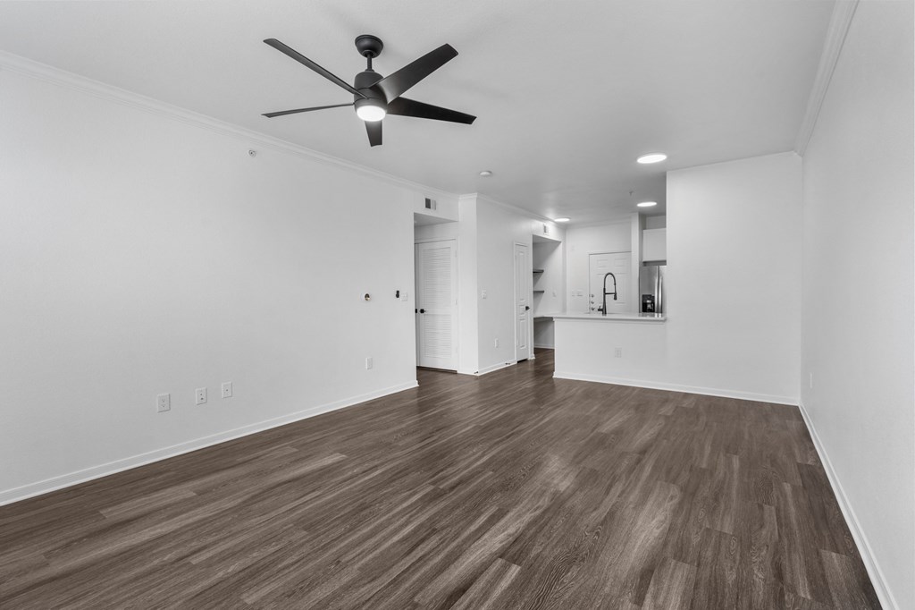 a bedroom with a ceiling fan and a kitchen in the background