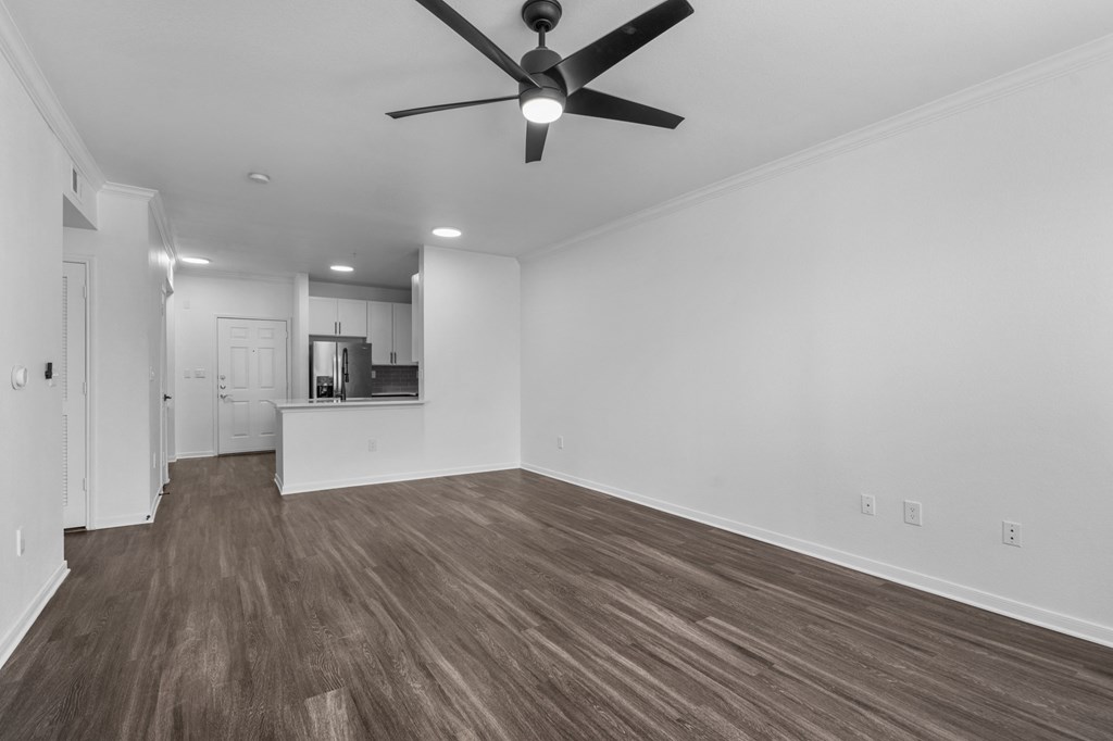 a bedroom with a ceiling fan and a kitchen in the background