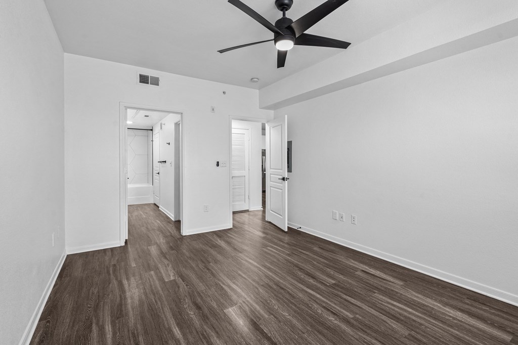 a bedroom with white walls and a ceiling fan