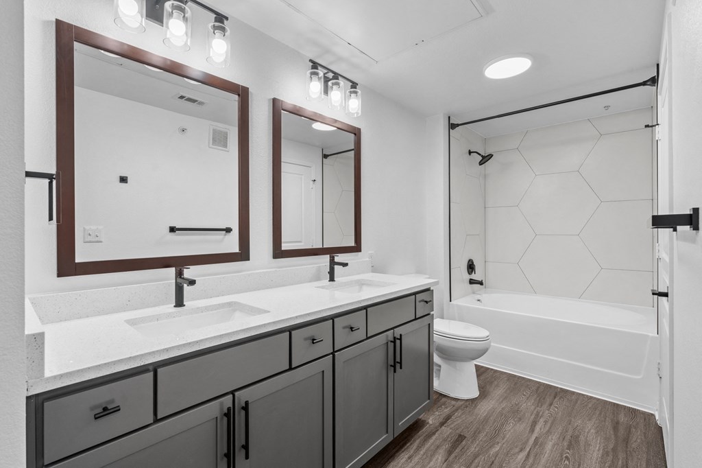 a bathroom with gray cabinets and a white bathtub