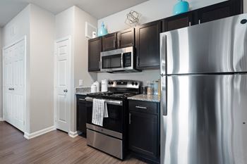 A kitchen with a stainless steel refrigerator, black oven, and microwave.