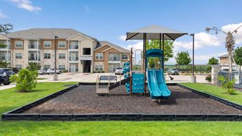 A playground with a blue slide and a brown building in the background.