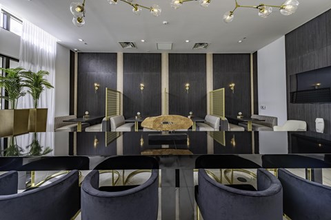 A black and gold dining room with a long table and chairs.