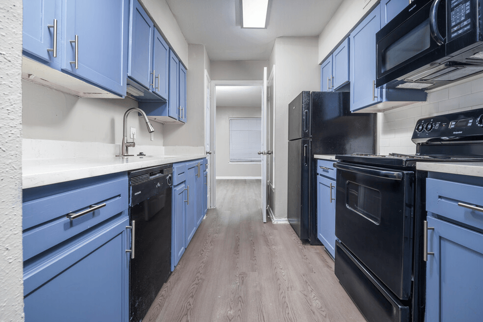 an empty kitchen with blue cabinets and black appliances