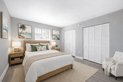 A bedroom with a large bed, a nightstand with lamps, a chair, and pictures on the wall.
