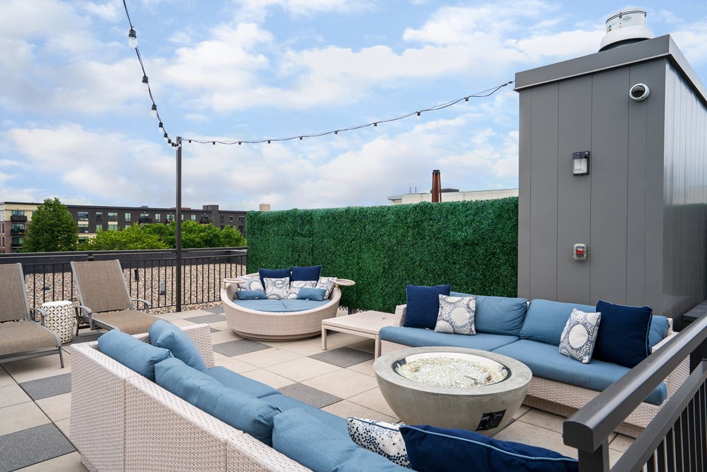 a rooftop terrace with couches and chairs and a fire pit