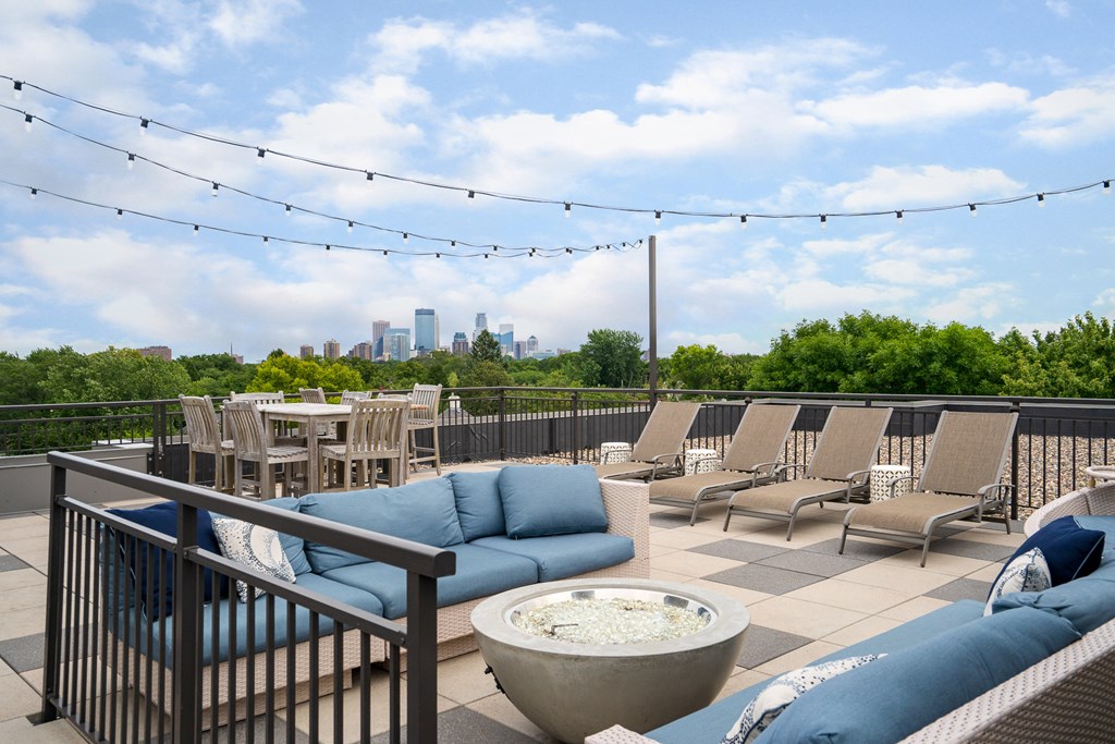 a rooftop patio with couches and chairs and tables and a view of the city