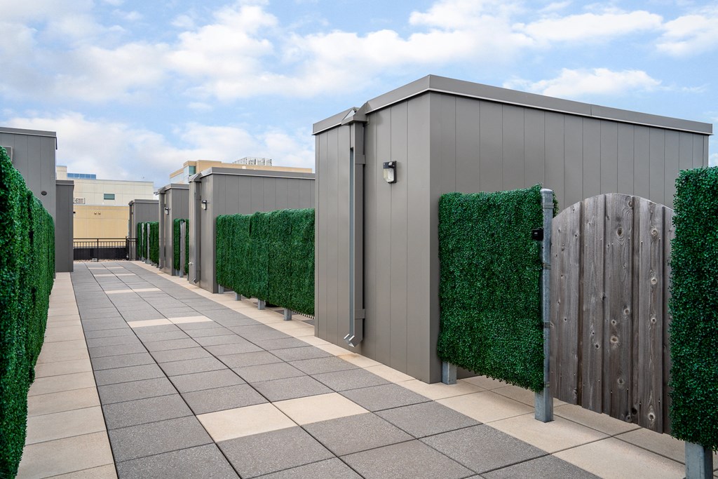 a row of sheds with green hedges and a wooden fence