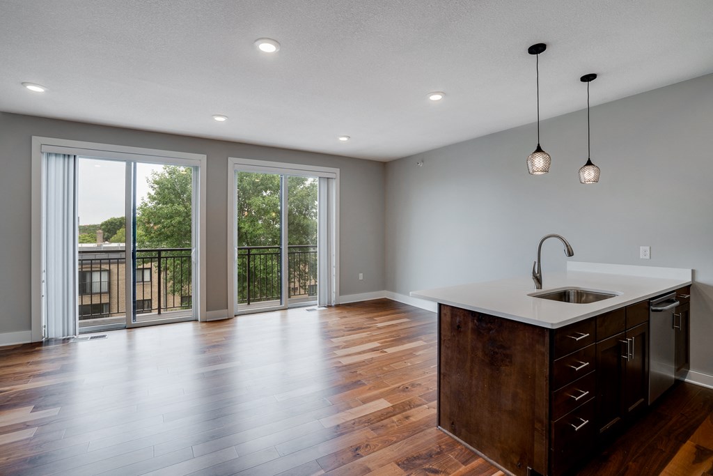 an empty living room with a kitchen and a balcony