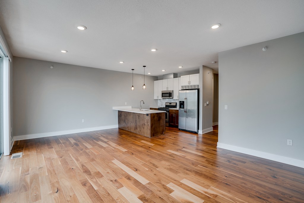 an open kitchen with a large island and wooden floors