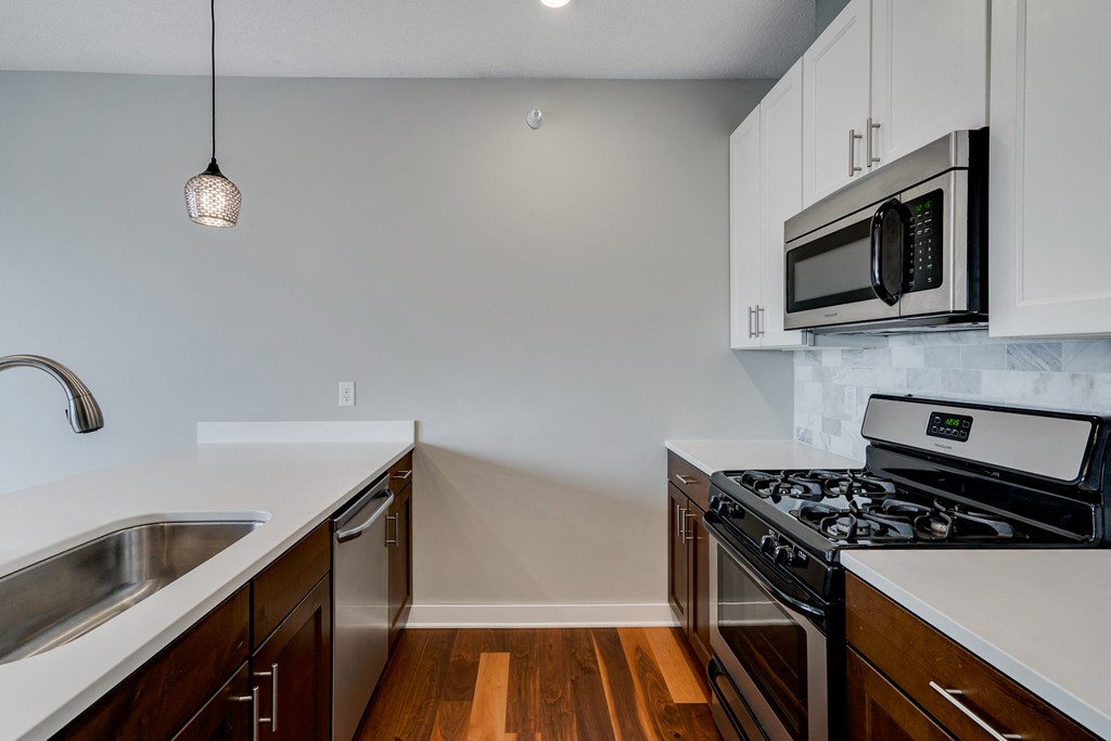 an empty kitchen with stainless steel appliances and white cabinets