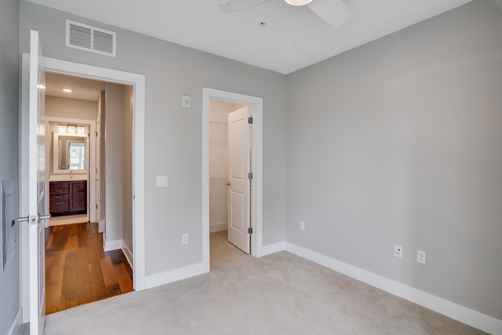 an empty bedroom with a hallway to a bathroom and a closet