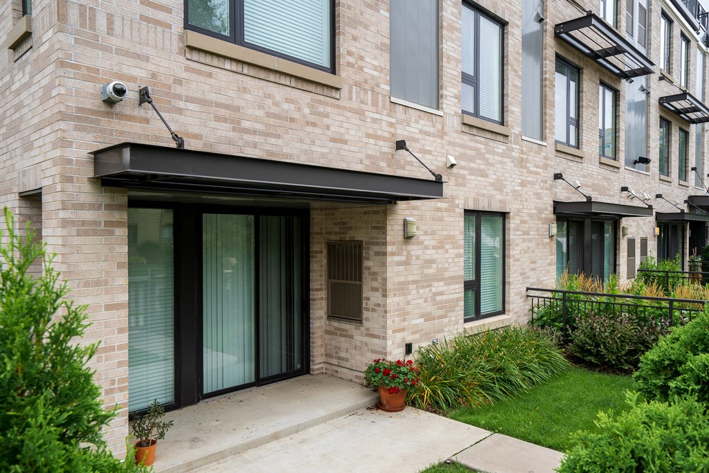 front entrance to a brick apartment building with a sidewalk and grass