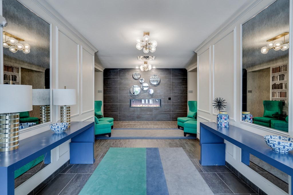 a lobby with blue counters and green chairs and a fireplace